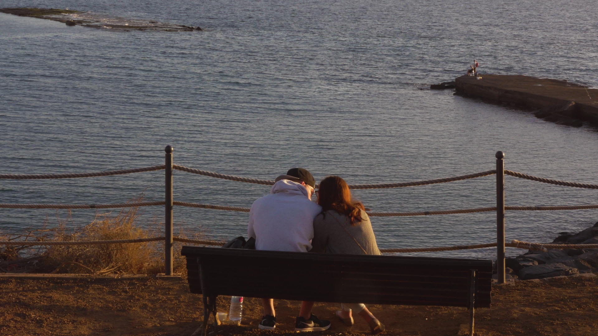 年轻夫妇坐在海边的长椅上视频的预览图
