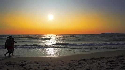 两对夫妇在日落的夏天在海滩上散步视频的预览图