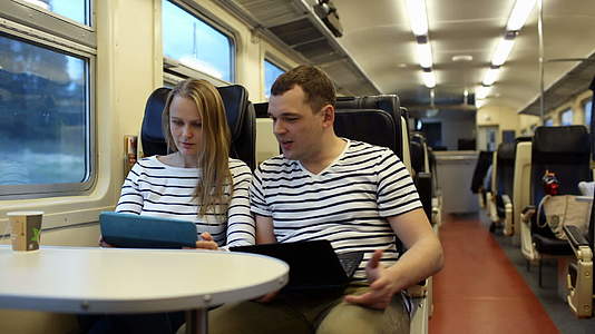 女人和男人在火车上用笔记本电脑说话视频的预览图