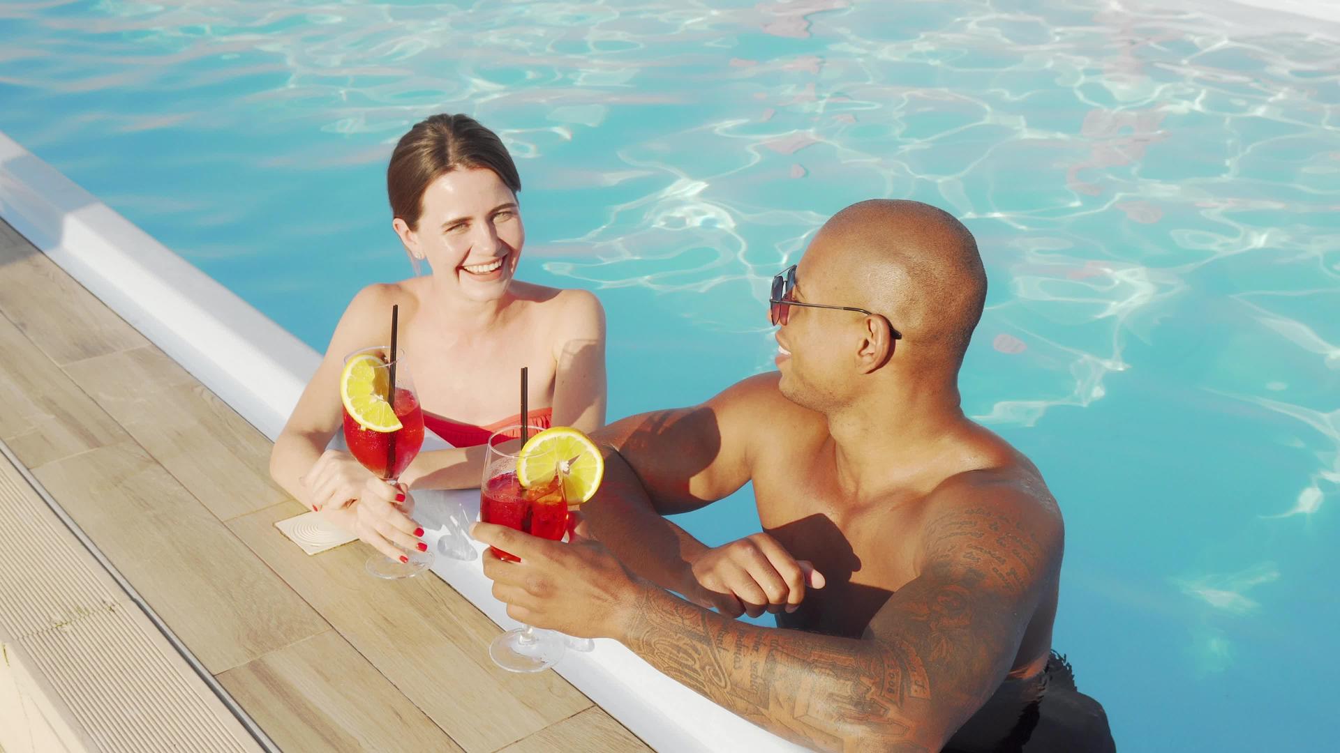 一对多民族幸福的多民族夫妇在游泳池里戴着杯子视频的预览图