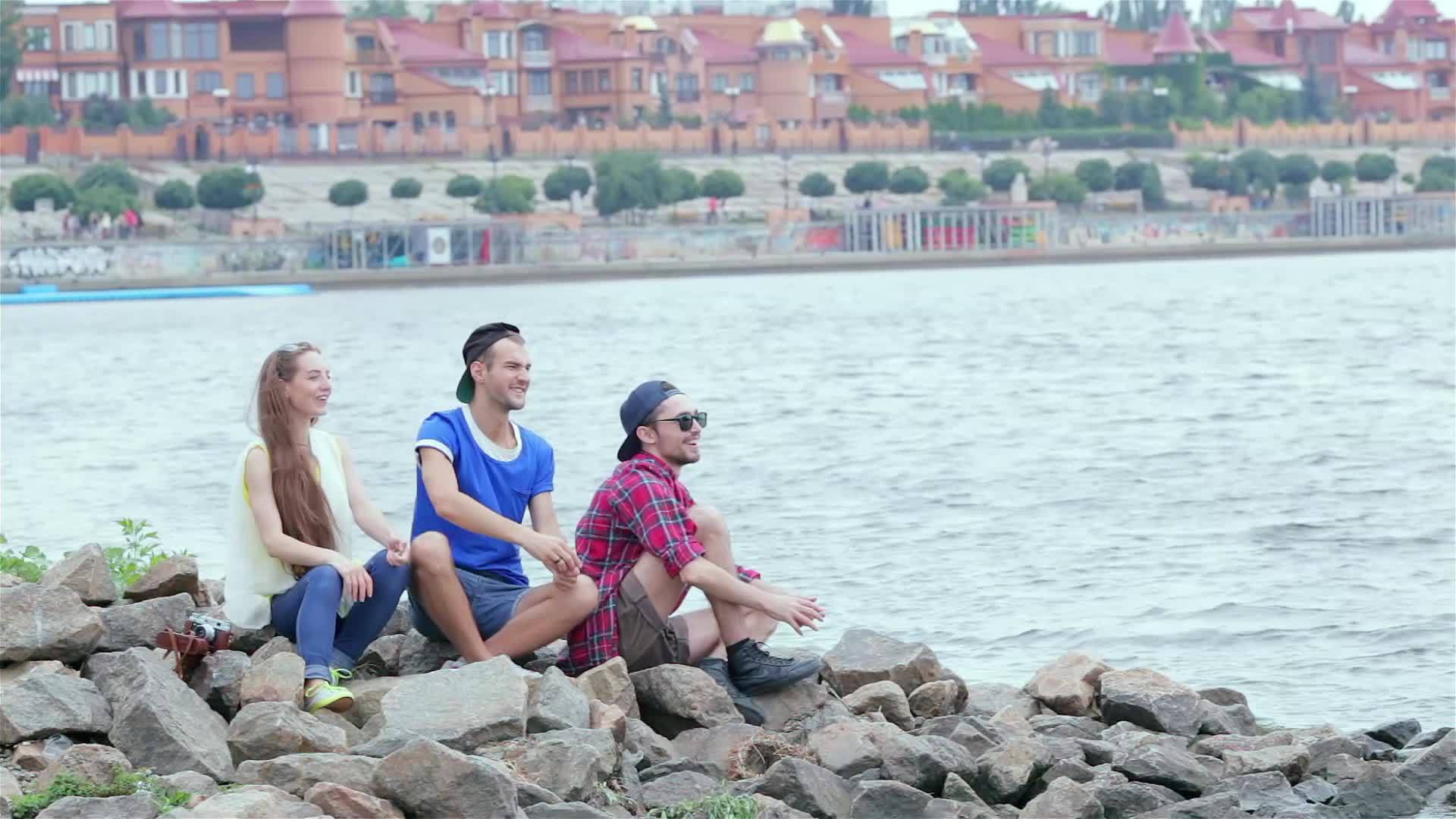 三个朋友坐在河上扔石头视频的预览图