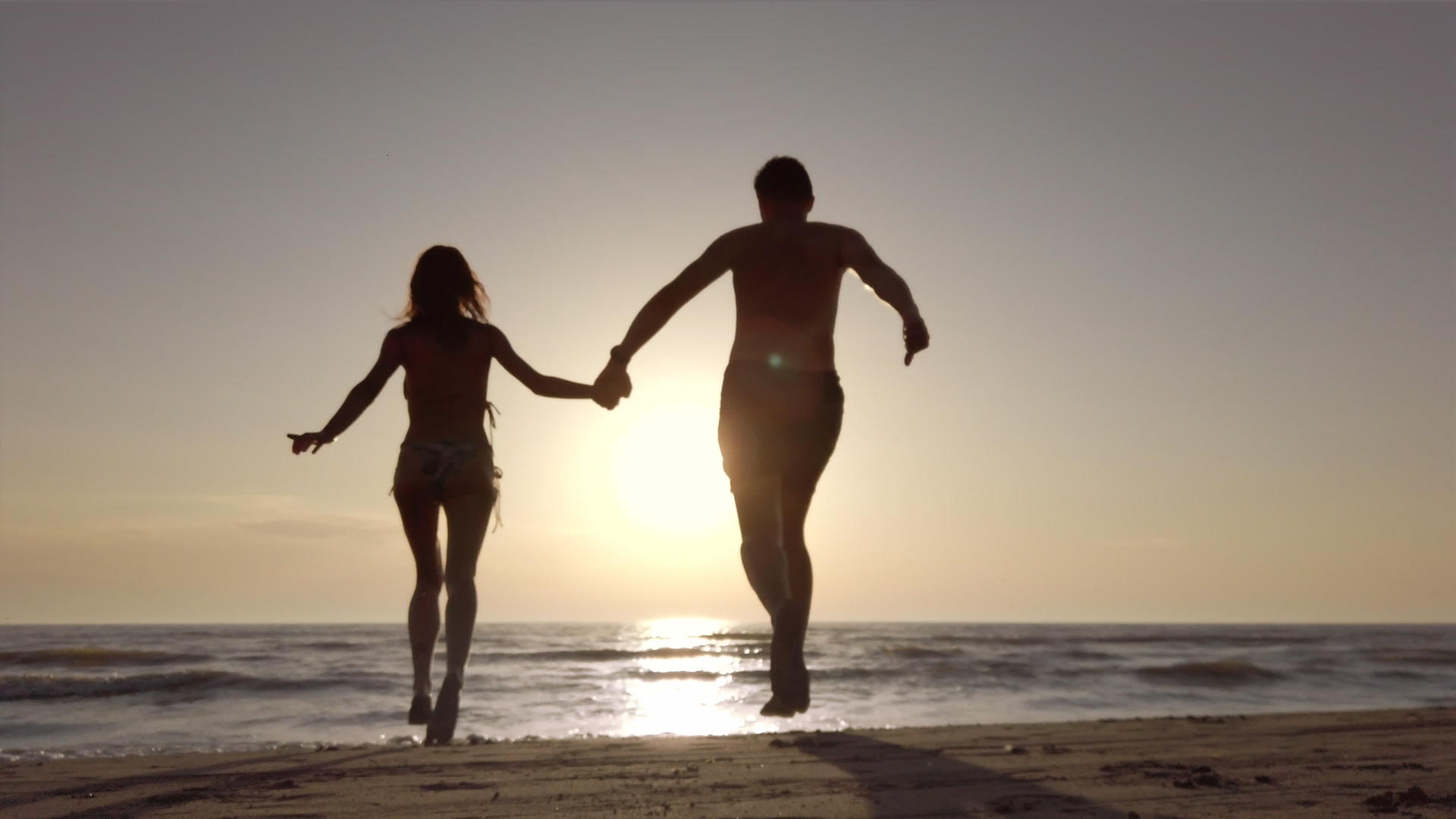 一对离婚的夫妇手牵手在海滩上跑到海边记录在60英尺处视频的预览图