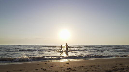 双休夫妇在海滩上握手在海里跑向相机视频的预览图
