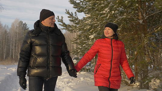 冬天男人和女人手牵手走在雪地松树林里视频的预览图