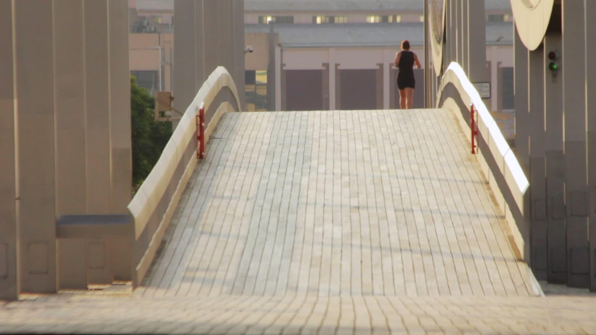 早晨穿过桥后视线的美女在桥上慢跑视频的预览图