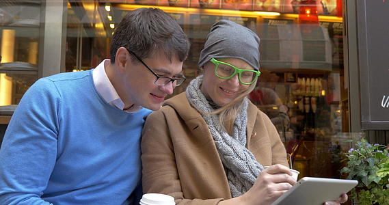 快乐情侣在街头咖啡馆使用数字电影视频的预览图