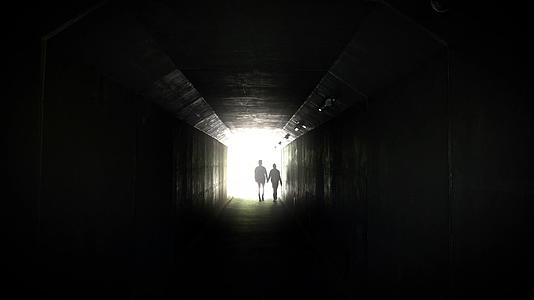 一对夫妇在地下行人隧道的尽头照亮了背景视频的预览图