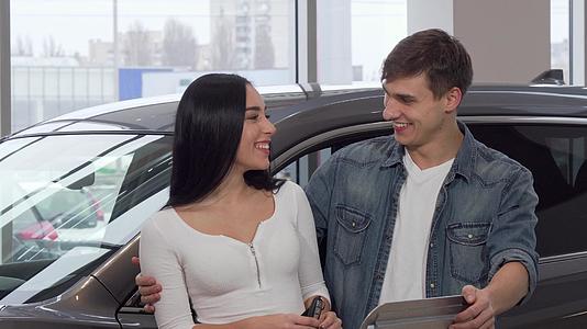 幸福的情侣在经销沙龙拥抱汽车钥匙视频的预览图