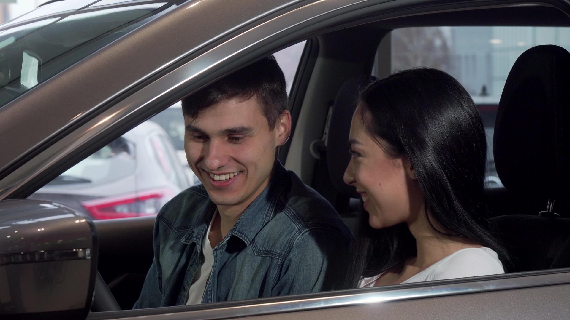 在分销沙龙中选择新车的年轻幸福夫妇视频的预览图