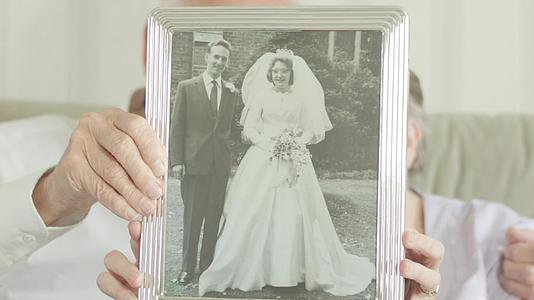 老年夫妇拿着婚前情侣的结婚照视频的预览图