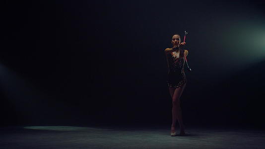 艺术体操运动员女性在黑色背景下展示体操技巧视频的预览图