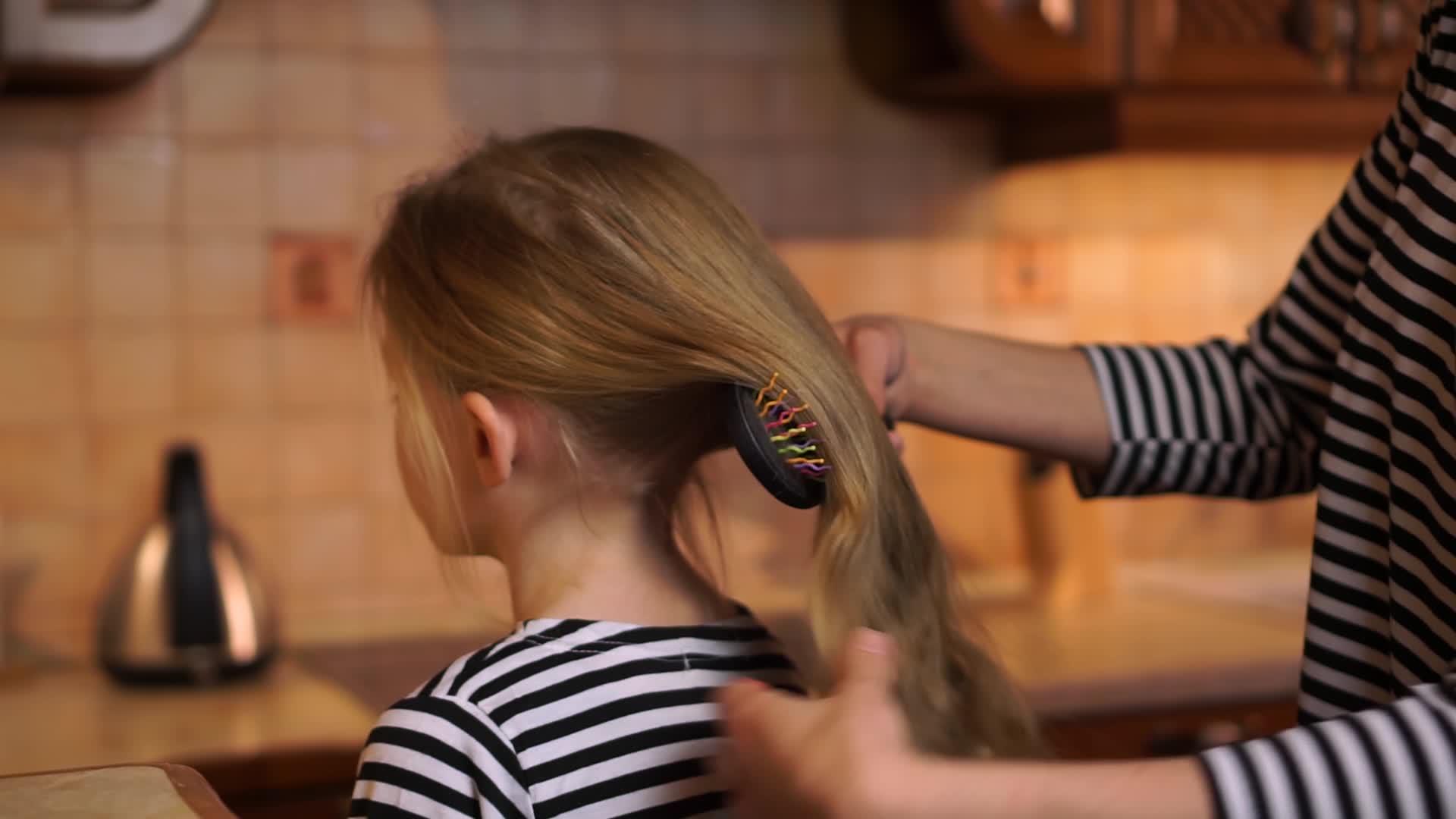 女儿在舒适的木制厨房里留着金发和长发穿着条纹衣服视频的预览图