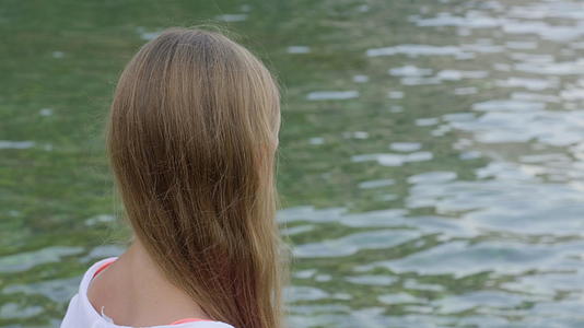 一个留着长发的女孩在夏天的海滩上寻找大海看着十几岁的女孩视频的预览图