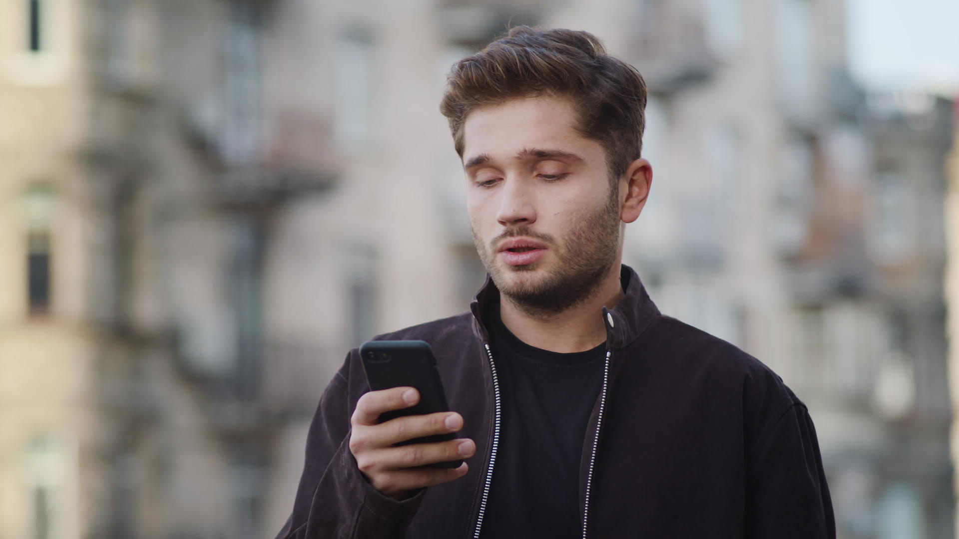冬天年轻男性用手机看户外视频视频的预览图