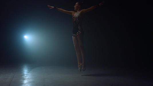 优雅的艺术体操女性在聚光灯下表演体操技巧视频的预览图