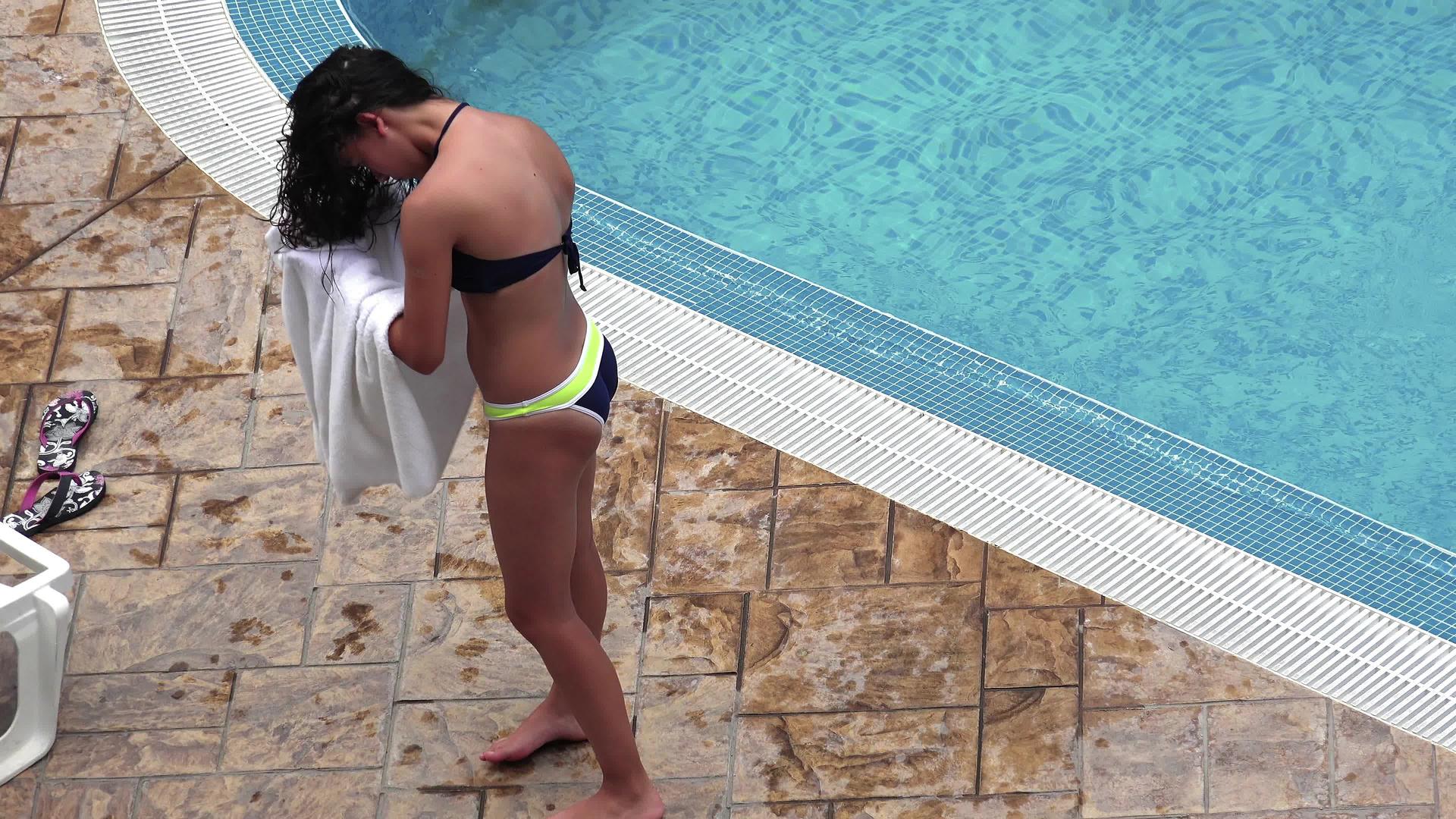 一个穿着白毛巾在游泳池边擦头发的漂亮女孩视频的预览图