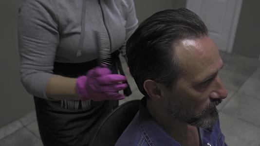 顾客看着相机微笑着他用手套和梳子做理发师的发型视频的预览图