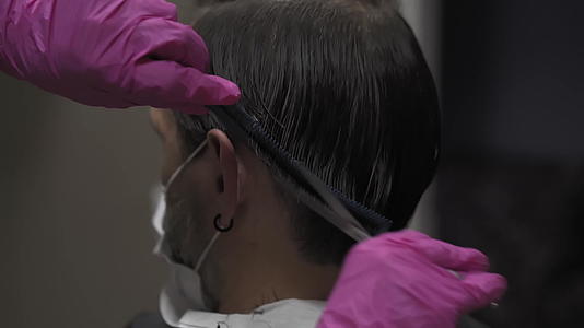 专业美发师准备在耳朵后面给一个年轻人剪头发视频的预览图