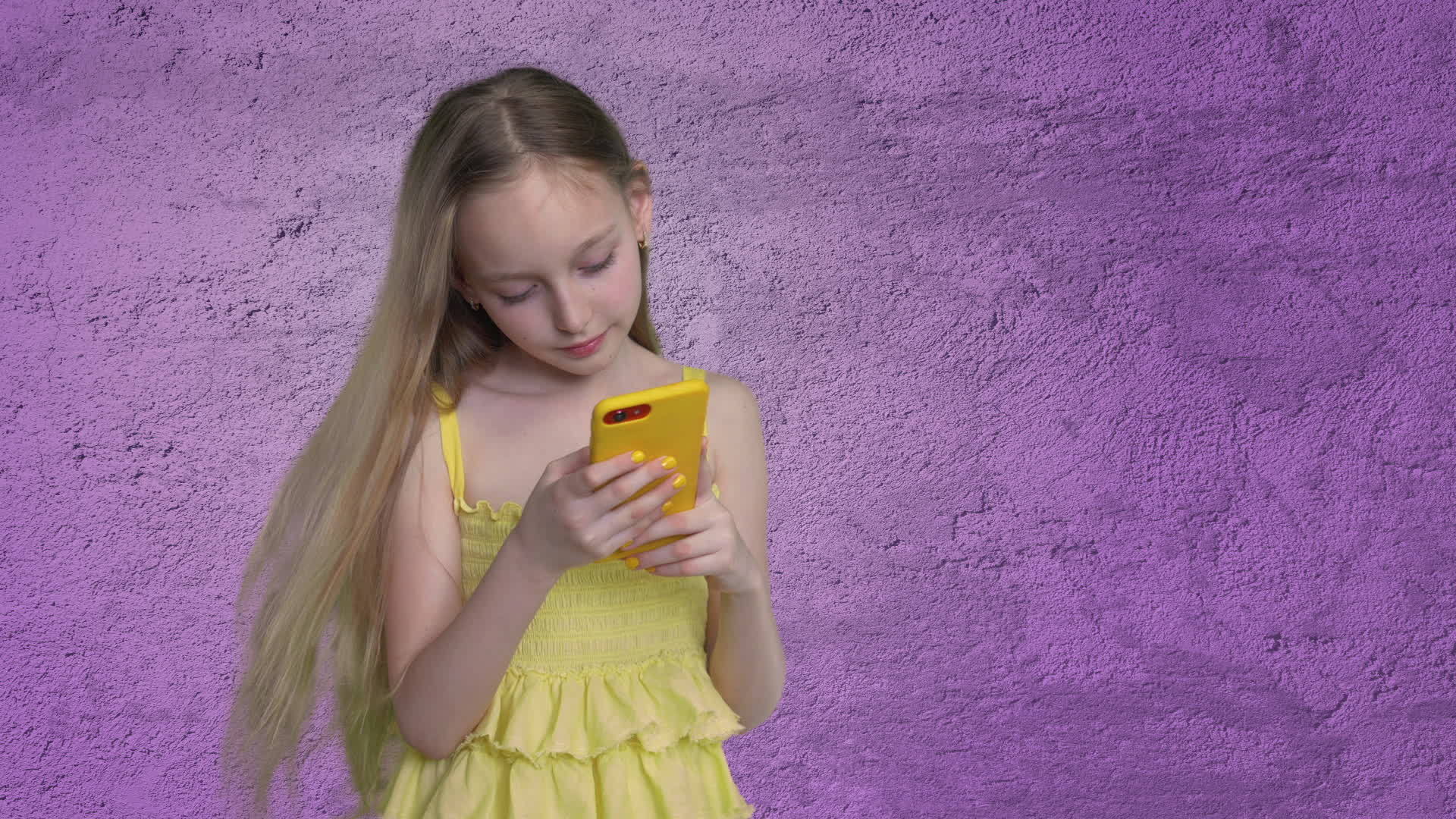 在紫罗兰色的墙壁背景上长发女孩看着手机漂亮的女孩在风中视频的预览图