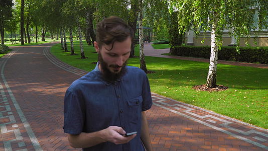 一个男孩走在大楼附近的公园里视频的预览图