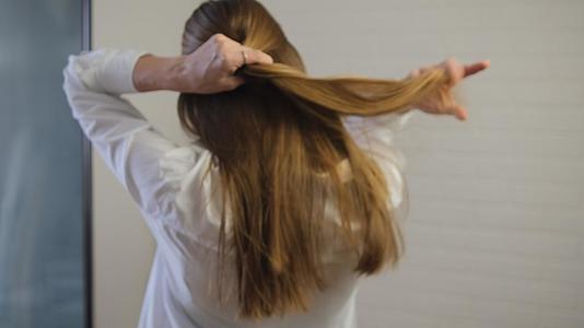 女孩把她光滑的金色长发梳成辫子视频的预览图