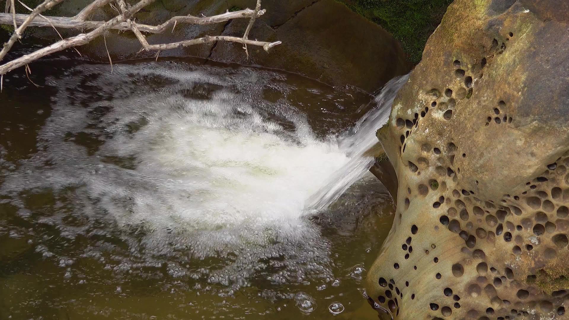 太平洋海岸美丽石头之间的快速流水瀑布视频的预览图