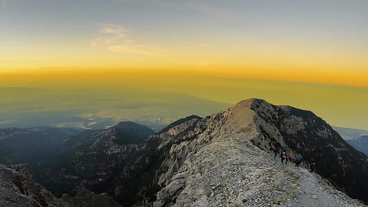 登山者从岩峰顶部下来在日落时最高的奥林马斯峰顶部视频的预览图