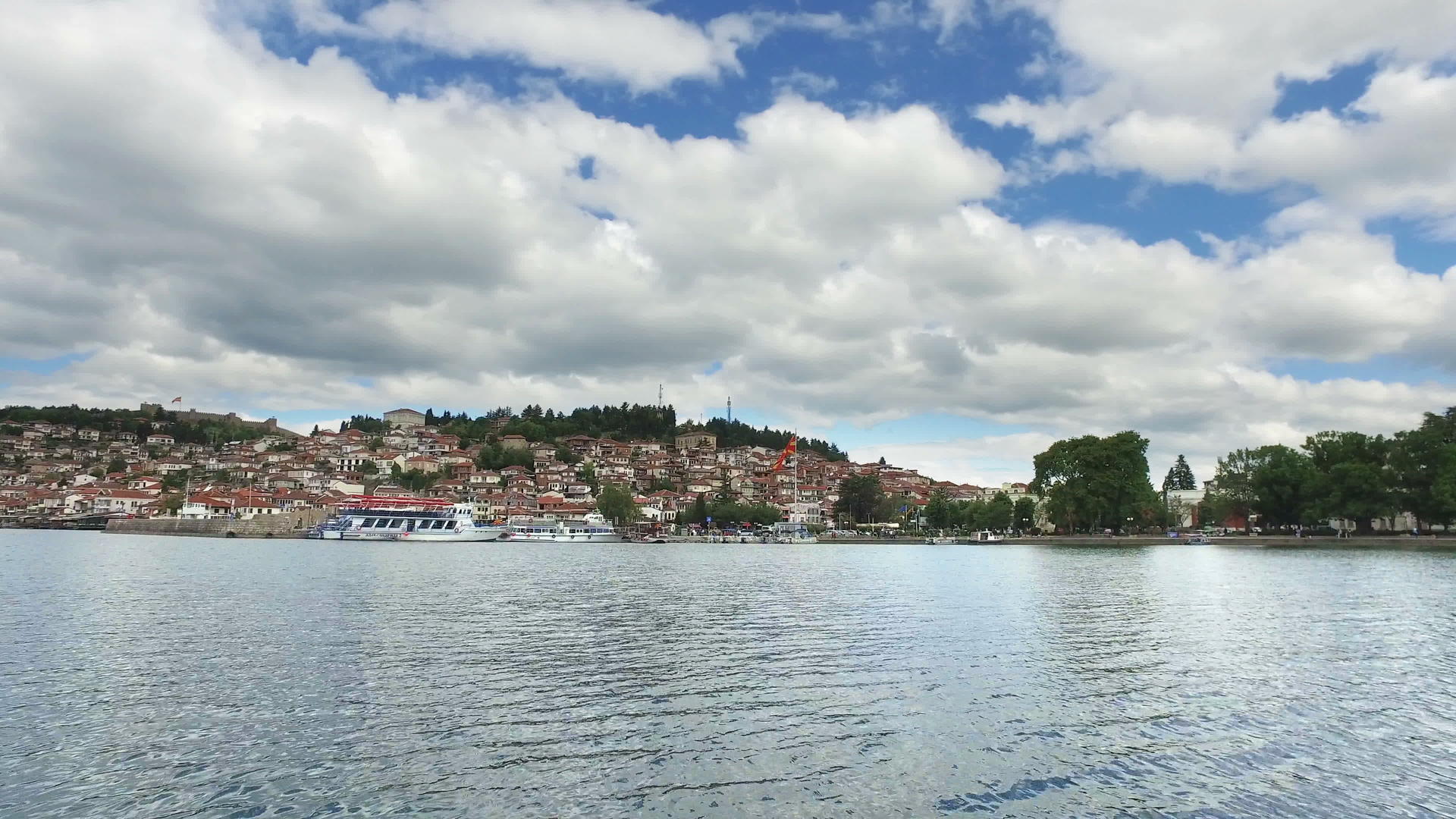 从奥赫里德城市建筑和港口的湖上移动船的场景视频的预览图