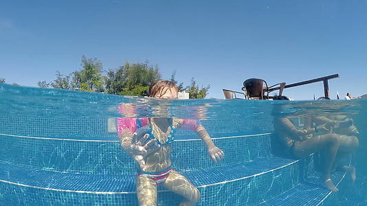 女孩追逐和拍摄相机慢动作半水下拍摄掌声热泳池视频的预览图