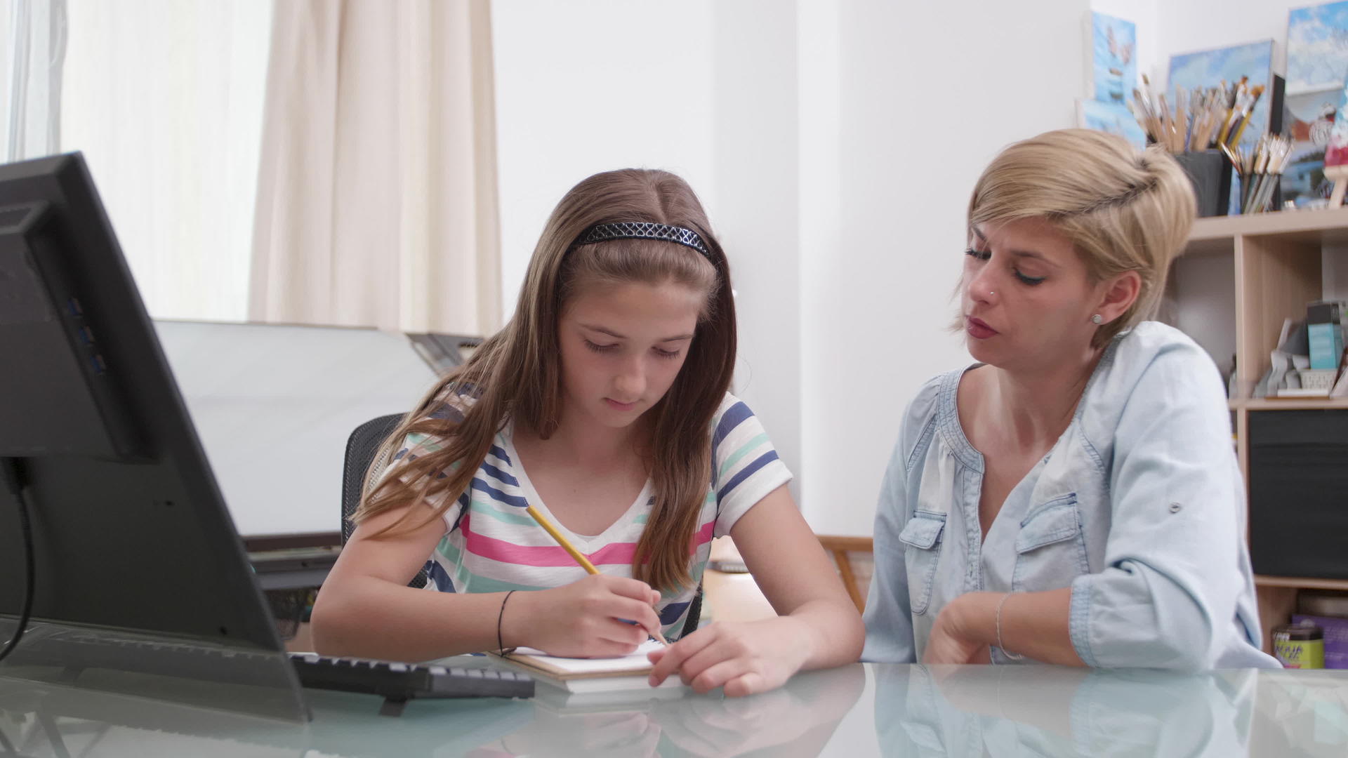 在笔记本上画画的女孩她的母亲和她说话视频的预览图