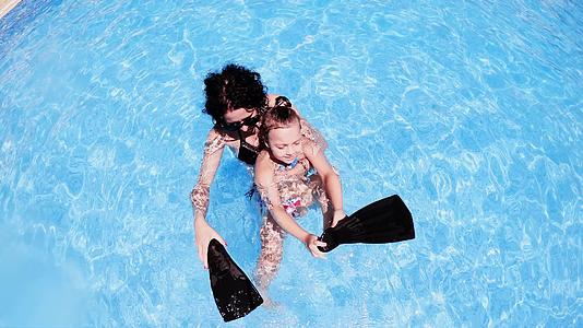 这位年轻快乐的母亲在游泳池里给她的小女儿上游泳课视频的预览图