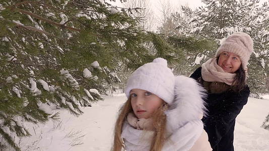 在寒冷的冬天 女儿和母亲一起走在雪林里视频的预览图