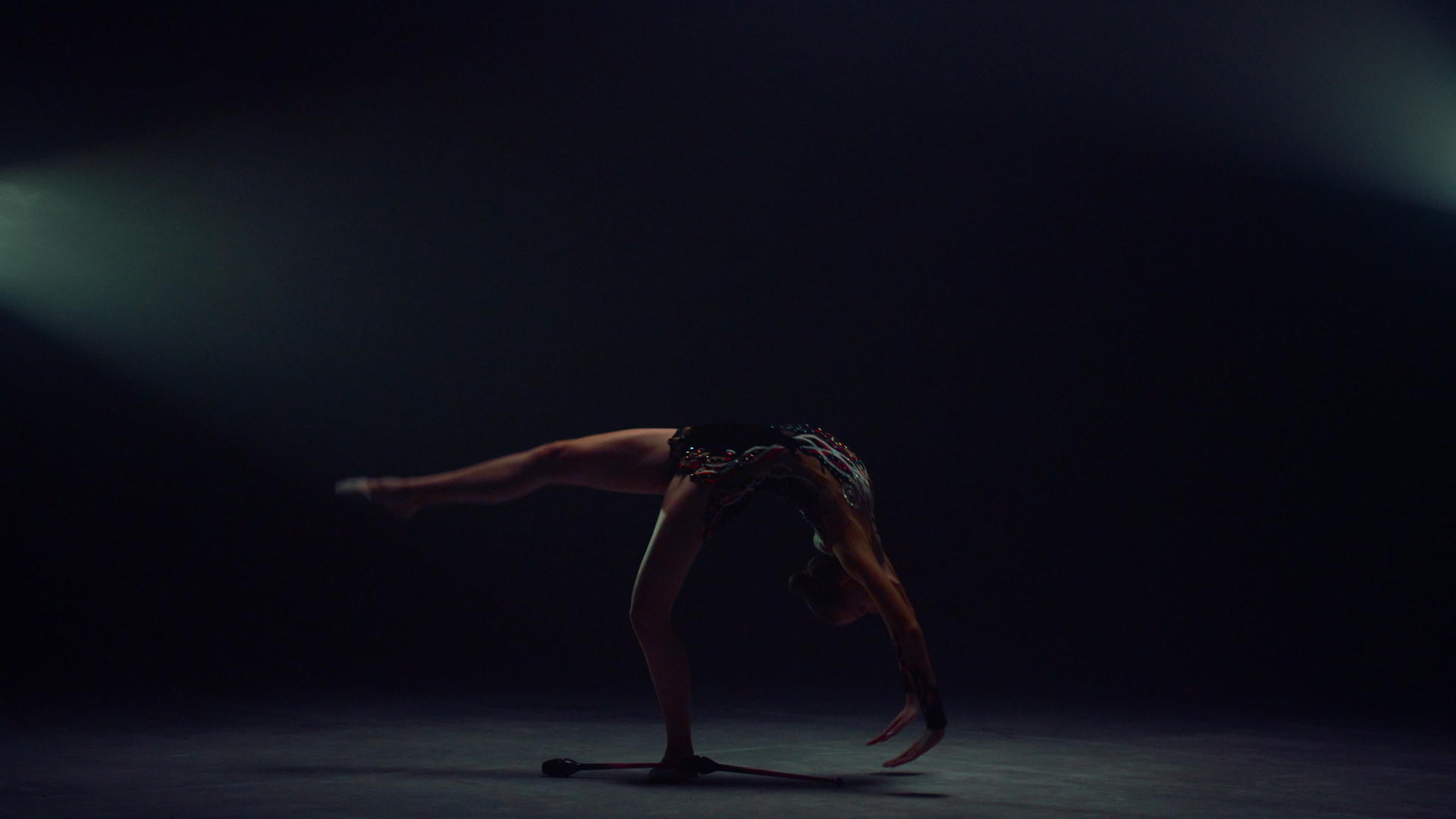 艺术体操运动员女孩在黑暗的空间里展示了她的体操技巧视频的预览图