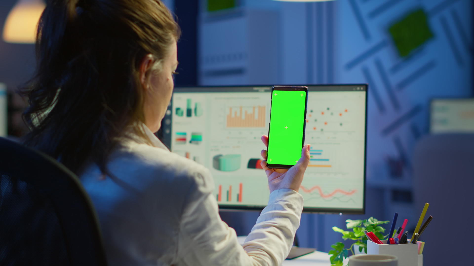 女性商人在绿屏上看智能手机的后视线视频的预览图