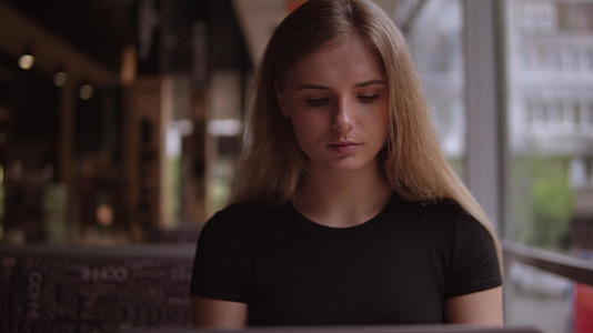 一个年轻的女士用笔记本电脑坐在桌子上的肖像视频的预览图