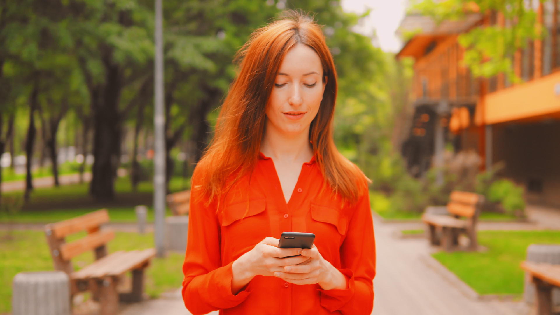 红头发的女性在户外智能手机上滚动触摸屏幕视频的预览图