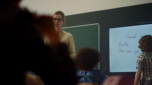 老师在课堂上叫小学生在交互式数字白板上写字视频的预览图
