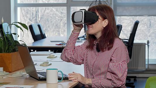 成熟的商业女性在工作场所使用虚拟现实头盔享受娱乐活动视频的预览图