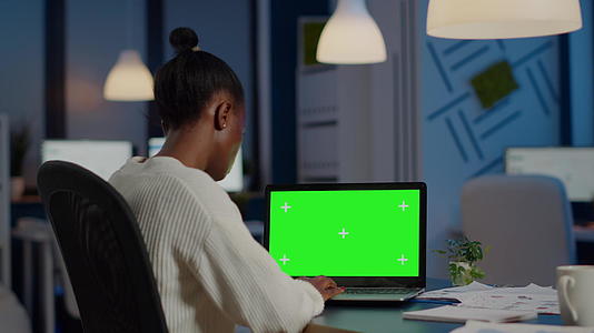 黑色商业女性用绿屏看笔记本电脑的后视线视频的预览图