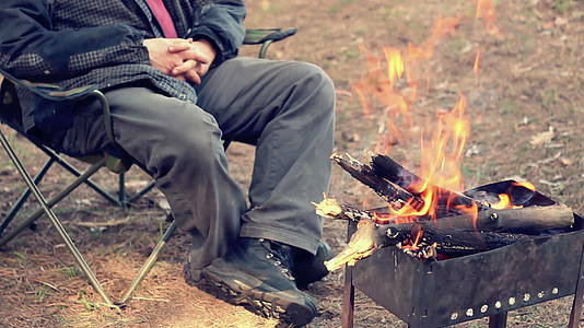人火附近的娱乐活动森林里的营火坐在营椅上视频的预览图