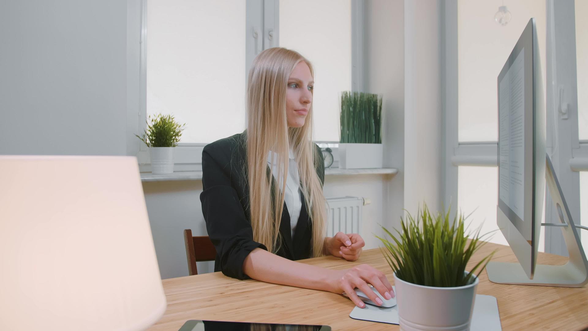 年轻女性坐在工作场所穿着商业套装用拇指看着相机视频的预览图