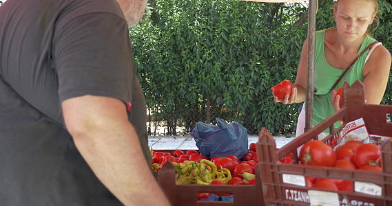年轻女性在街头卖家的摊位上买西红柿视频的预览图