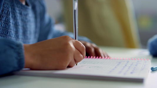 女孩在教室的书桌笔记本上写字在学校做作业视频的预览图