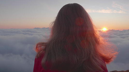 孤独的年轻女子在五颜六色的粉色日出时站在云层之上视频的预览图