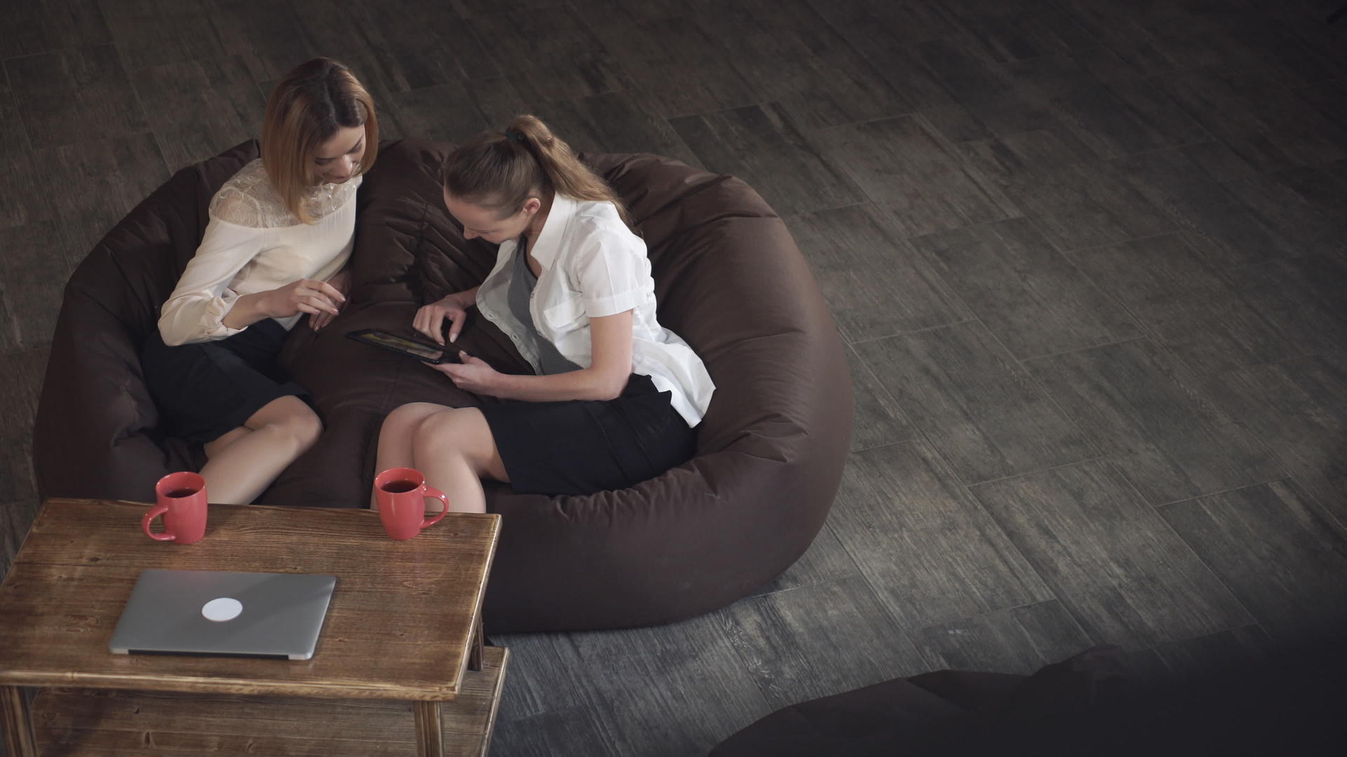 两个女人用平板电脑坐在咖啡馆的沙发上视频的预览图