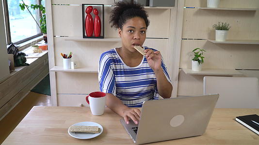 女性在电脑上吃健康的零食和工作视频的预览图