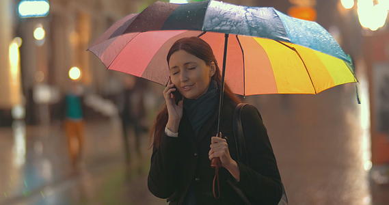 黑发女人在雨天在街上打电话视频的预览图