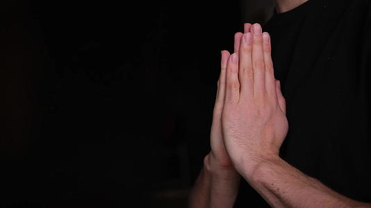 那家伙祈祷一个男人在黑色模糊的背景下双手合十祈祷视频的预览图