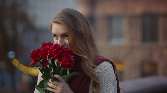 美女在户外街头约会手捧玫瑰闻花香表情幸福视频的预览图