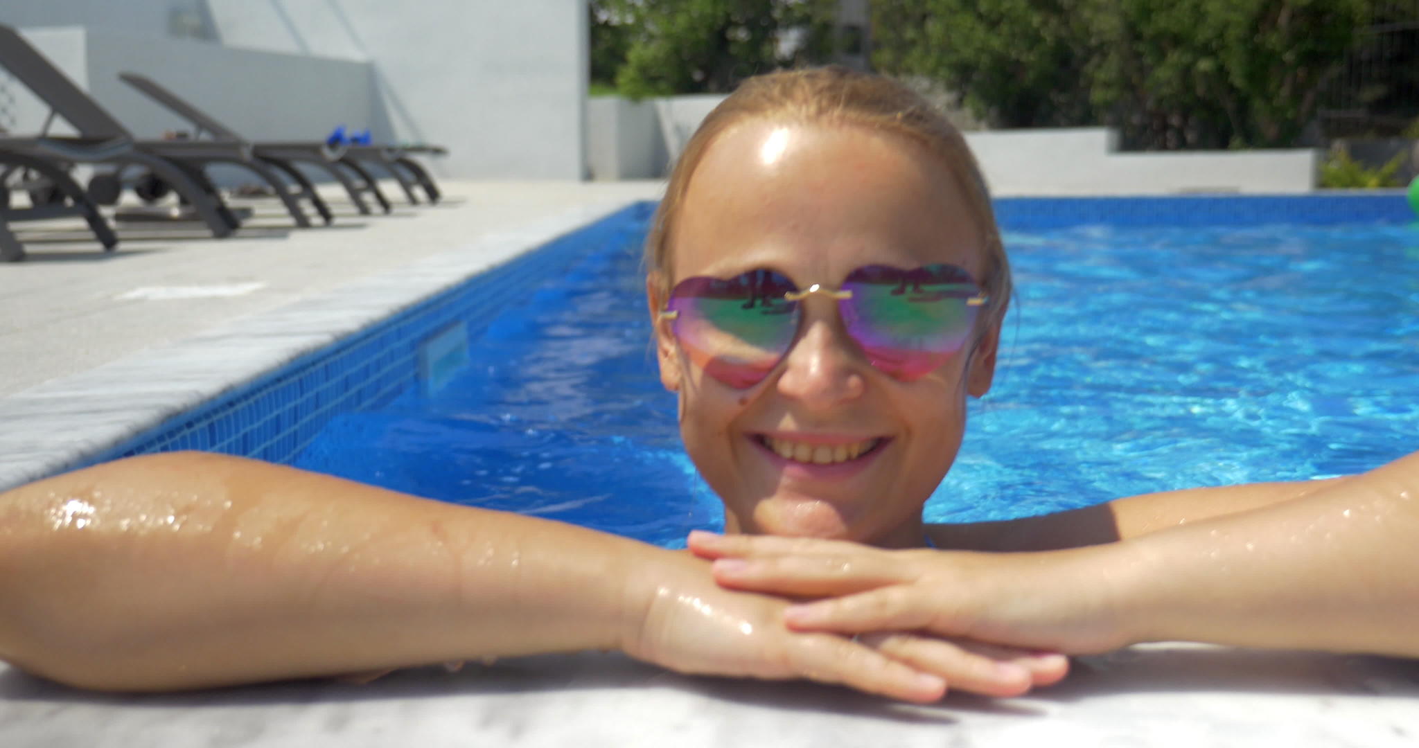 穿着太阳镜的女人在游泳池里享受阳光明媚的一天视频的预览图